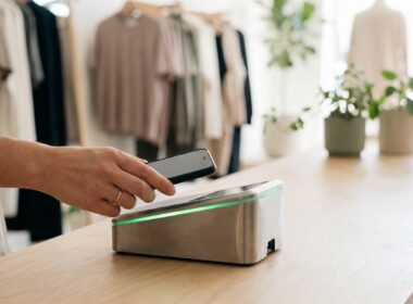 Hand hält Smartphone über ein kontaktloses Kartenterminal
